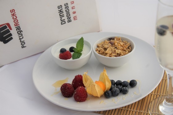 A large bowl of sweet honey-clustered granola served with yoghurt or milk and a side of seasonal fruits.